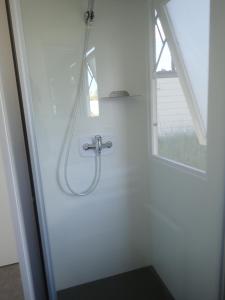 una doccia in un bagno bianco con finestra di Ferienpark Süderstapel a Süderstapel