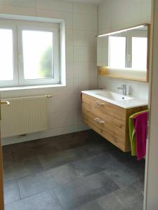 La salle de bains est pourvue d'un lavabo, d'un miroir et de 2 fenêtres. dans l'établissement Ferienwohnung Kern, à Bodensdorf