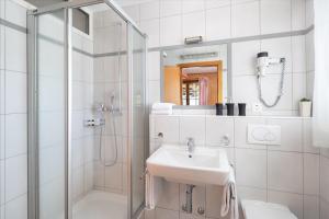 biała łazienka z umywalką i prysznicem w obiekcie Petit Paradis w mieście Crans-Montana