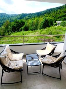 three chairs and a table on a balcony with a view at Relax View Ap with Private Parking in Sinaia