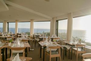 ein Esszimmer mit Tischen, Stühlen und Fenstern in der Unterkunft Caloura Hotel Resort in Caloura