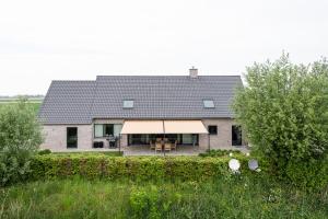 a large house with a large window and a roof at Polderwoning 'Cleylantshof' in Sint-Laureins
