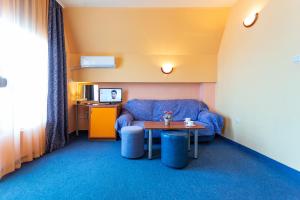 a living room with a blue couch and a table at Family Hotel Jemelly in Obzor