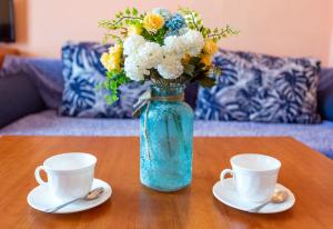 a blue vase with flowers and two cups on a table at Family Hotel Jemelly in Obzor