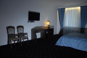 a hotel room with a bed and a desk with a television at Homestay Birutes Uostas Palanga in Šventoji
