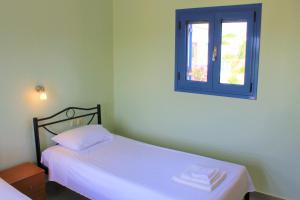 1 dormitorio con cama blanca y ventana en Stamna Farm, en Romanós