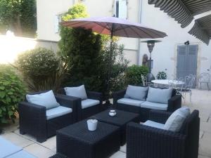 an outdoor patio with wicker chairs and an umbrella at De la Chambre au Jardin in Belleville-en-Beaujolais