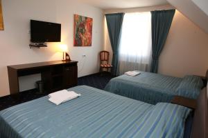 a hotel room with two beds and a desk and a television at Homestay Birutes Uostas Palanga in Šventoji