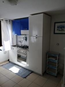 una cucina bianca con piano cottura e frigorifero di Elisa Home Casa Vacanze a Sottomarina