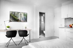 eine weiße Küche mit 2 Stühlen und einem Tisch in der Unterkunft Favorit Serviced Apartments in Ludwigsburg