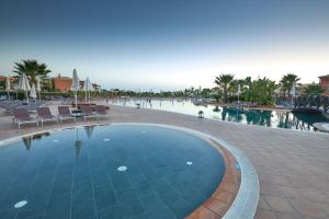 a swimming pool in a resort with chairs and water at Monte Santo Resort in Carvoeiro