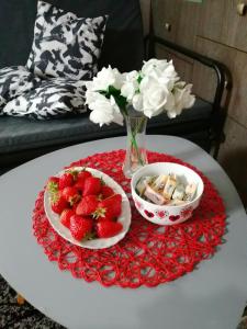 un tavolo con due ciotole di fragole e un vaso di fiori di Apartman Red wall a Čačak