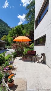 a patio with a bench and an umbrella and flowers at Casa 21 in Sonogno