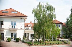 a tree in front of a white house at Hotel Villa Hubertus Kutno in Kutno