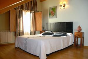 Un dormitorio con una gran cama blanca y una ventana en Casa Rural Casa Colom, en Espot