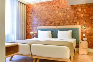- une chambre avec un grand lit et un mur en briques dans l'établissement My Story Hotel Tejo, à Lisbonne