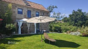 an umbrella and a bench in the yard of a house at A casa dos Parladoiros in Mos