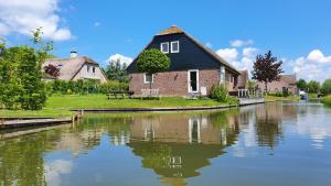 een huis aan de kant van een rivier bij Water & Meadow cottage in Central Holland 2A & 2C in Schoonrewoerd