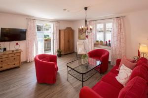 a living room with a red couch and red chairs at Haus Wienertoni in Grainau