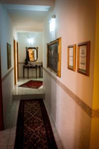 a hallway with paintings on the wall and a rug at Maison De Lussy in Piazza Armerina