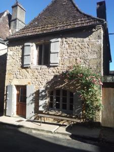 una vieja casa de piedra con una puerta y flores en Maison de La LAFONE, en Domme