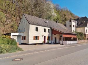 eine weiße Scheune mit schwarzem Dach an der Straßenseite in der Unterkunft die rote Ente in Mürlenbach