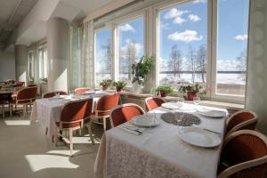 a dining room with tables and chairs and large windows at Kylpylähotelli Pohjanranta in Keminmaa