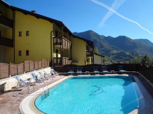 a swimming pool in front of a hotel with mountains at Residence ai Tovi in Ledro