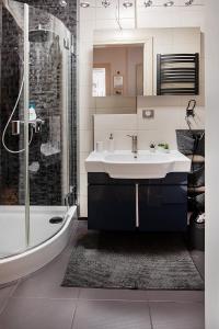 a bathroom with a tub and a sink and a shower at Movie Apartment Jeżyce in Poznań