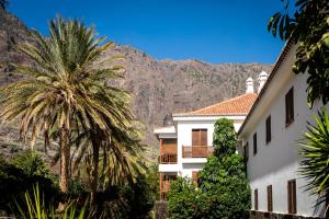 a building with a palm tree and mountains in the background at Parador de El Hierro in Las Casas