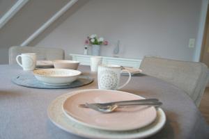 una mesa con platos y utensilios encima en Haus Ruh di ut Wohnung LUV, en Kellenhusen
