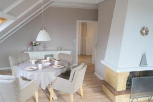 a white dining room with a table and chairs at Haus Ruh di ut Wohnung LUV in Kellenhusen