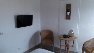 Zimmer mit einem TV, einem Tisch und Stühlen in der Unterkunft Hotel Les Esseppes in LʼÉpine