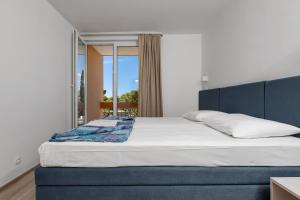 Schlafzimmer mit einem Bett mit blauem Kopfteil und einem Fenster in der Unterkunft Hotel Alem in Baška Voda