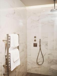Łazienka z prysznicem wyłożona jest białymi kafelkami. w obiekcie Weymouth Mews w Londynie