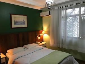 Dormitorio verde con cama y ventana en Residencial Pantanal Vila Mariana, en São Paulo