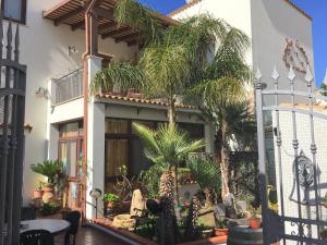 a house with palm trees in the courtyard at Baglio Cusenza Rooms in San Vito lo Capo