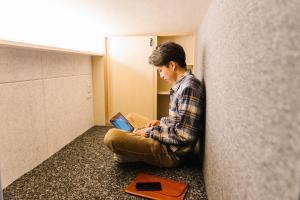 a man sitting on the floor with a laptop at unito CHIYODA in Tokyo
