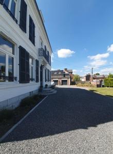 een lege straat naast een wit gebouw bij Chambres d'Hôtes des Rouets in Fourmies