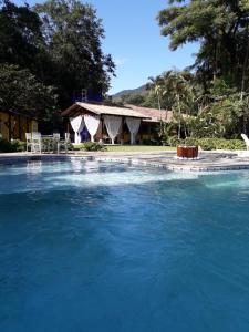 uma grande piscina de água azul em frente a uma casa em Casa Linda - Piscina Ampla - Jacuzzi - Imenso Jardim em São Sebastião