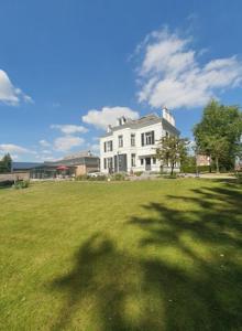 a large white house in a field of green grass at Chambres d'Hôtes des Rouets in Fourmies