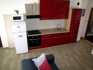 cocina con armarios rojos y fogones en Apartments Klanac, en Zadar