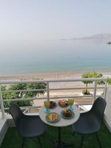 a table with a plate of food on a balcony overlooking the beach at FantaSea Apartments in Haraki +13 photos