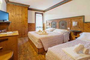 a hotel room with two beds and a television at Hotel Alemagna in San Vito di Cadore