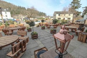 a patio with wooden tables and benches and trees at The Pooley Bridge Inn in Pooley Bridge