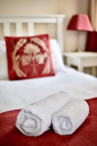 ホリーヘッドにあるWitchingham B&Bのベッドの上にタオル2枚(赤い枕付)