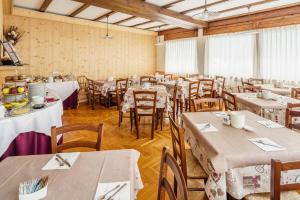 uma sala de jantar com mesas e cadeiras com toalhas de mesa brancas em Hotel Alemagna em San Vito di Cadore