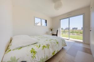 een witte slaapkamer met een bed en een groot raam bij TI LAOUEN - 300 m de la plage in Sarzeau