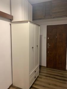 ein weißer Schrank in einem Raum mit einer Holztür in der Unterkunft Apartament z widokiem Tarnowskie Góry in Tarnowitz