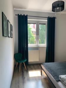 - une chambre avec une chaise verte et une fenêtre dans l'établissement Apartament z widokiem Tarnowskie Góry, à Tarnowskie Góry